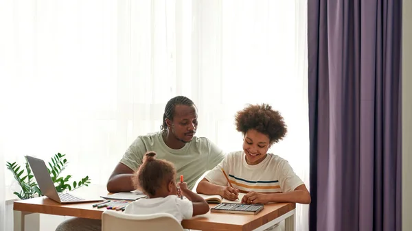 Pai ajuda filho com lição de casa enquanto menina desenho — Fotografia de Stock