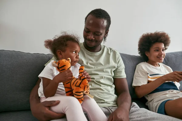 Μαύρη οικογένεια ανάπαυσης και περνούν το χρόνο τους στον καναπέ στο σπίτι — Φωτογραφία Αρχείου