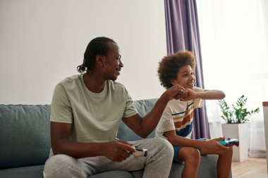 Baba ve oğul video oyunu oynarken yumruk tokuşturuyorlar.