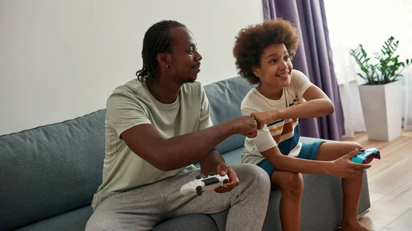 Negro padre e hijo jugando videojuego en sofá —  Fotos de Stock