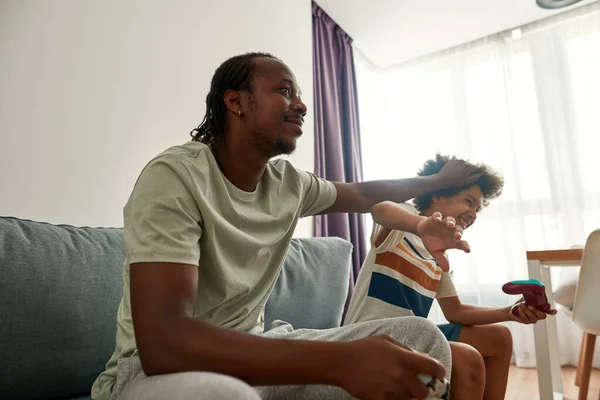 Černošky otec hladí syna, zatímco oni hrají videohry — Stock fotografie