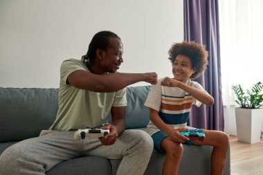 Siyah baba ve oğlu evde video oyunu oynuyorlar.