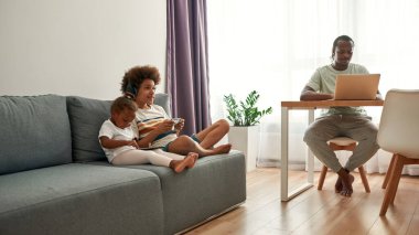 Çocuklar kanepede dinlenirken, babam dizüstü bilgisayar kullanıyor.