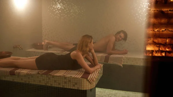 Casal caucasiano deitado na sauna quente finlandesa — Fotografia de Stock