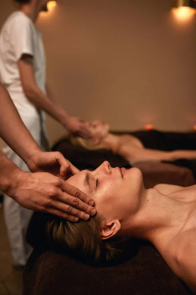 Corte de massagistas fazendo massagem na cabeça do casal — Fotografia de Stock