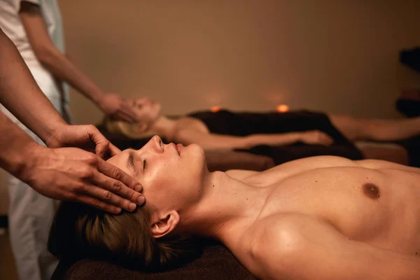 Vista lateral de massagistas fazendo massagem na cabeça do casal — Fotografia de Stock