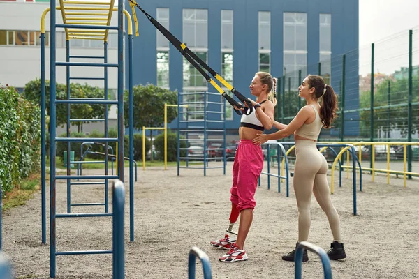 Engelli arkadaşının sırt egzersizi yapmasına yardım eden kadın