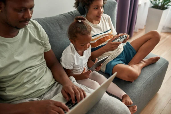 Svart familjerum vila och använda digitala enheter hemma — Stockfoto