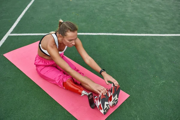 Engelli sporcu kız, spor minderinde bacaklarını ısıtıyor. — Stok fotoğraf