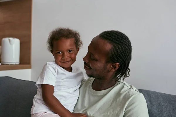 Otec objímající radostnou dceru na gauči doma — Stock fotografie