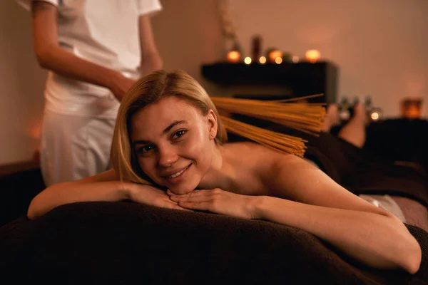 Masseur fazer massagem nas costas de mulher jovem com paus — Fotografia de Stock