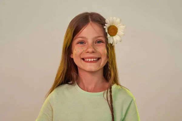 Chica con flor de manzanilla en el pelo mira a la cámara —  Fotos de Stock