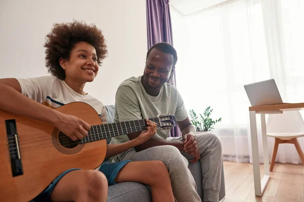 흑인 아버지는 아들 이 어쿠스틱 기타를 연주하는 모습 — 스톡 사진