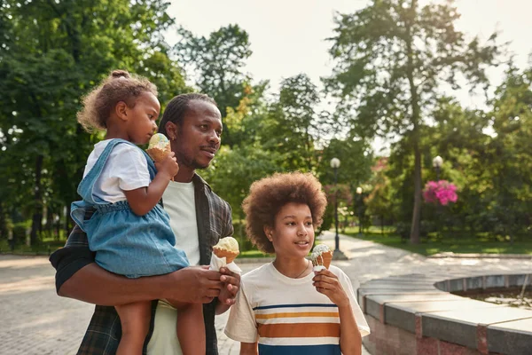 Mladá černošky rodina jíst zmrzlinu kužely v parku — Stock fotografie