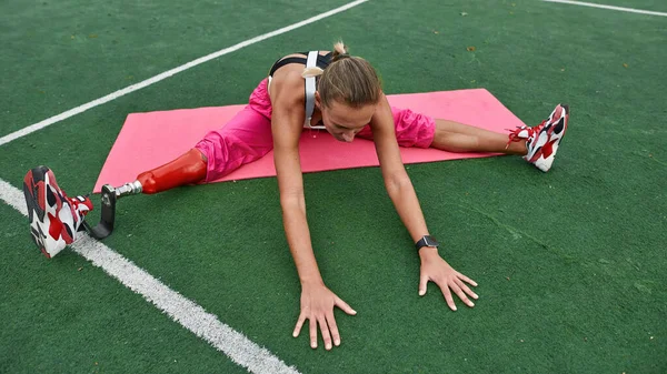 Disabled sports girl stretching on athletic field