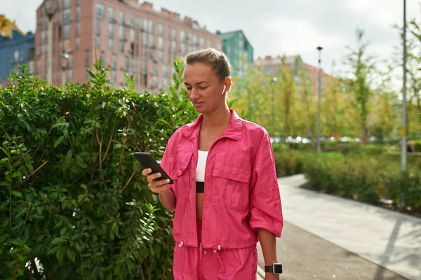 Chica atlética usando teléfono inteligente en la plaza de la ciudad —  Fotos de Stock