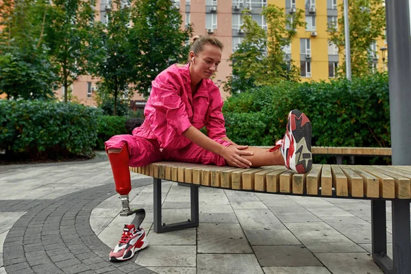 Disabled sports girl warming up on bench in city