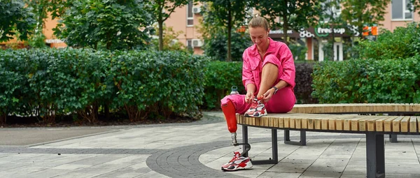 Disabled athletic girl sitting and tie shoelaces — Stock Photo, Image