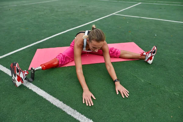 Disabled sports girl warming up on athletic field