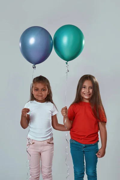 Dos chicas sosteniendo globos y mirando a la cámara —  Fotos de Stock