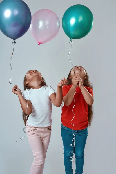Niñas felices sosteniendo globos y mirando hacia arriba —  Fotos de Stock