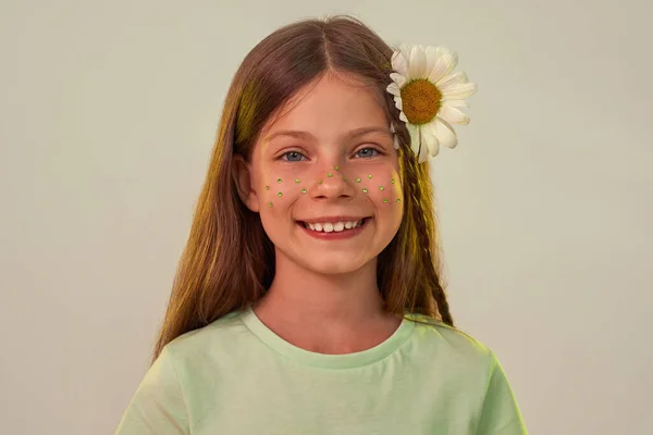 Sonriente chica con manzanilla en el pelo mira a la cámara —  Fotos de Stock
