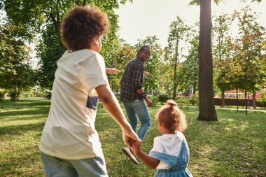 Genç siyahi aile yeşil parktaki çimlerde oynuyor.