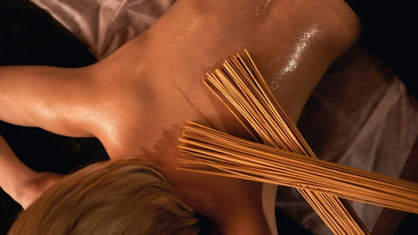 Masajista hacer masaje de espalda de chica con palos de bambú — Foto de Stock