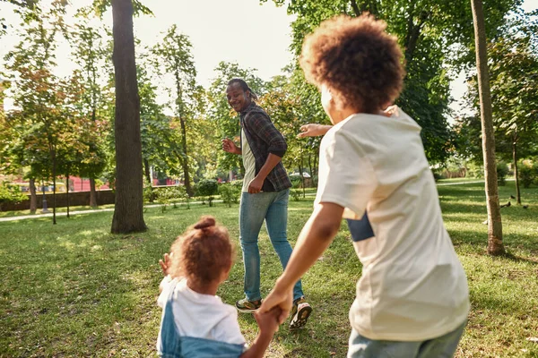Erkek ve kız kardeş avuçlarını çeker baba.