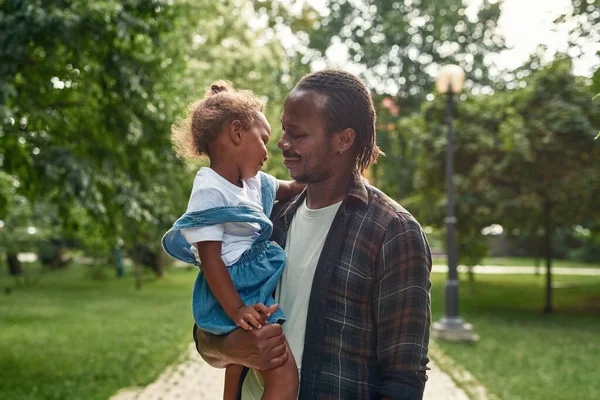 Černý táta držet a obejmout dceru v náručí v parku — Stock fotografie
