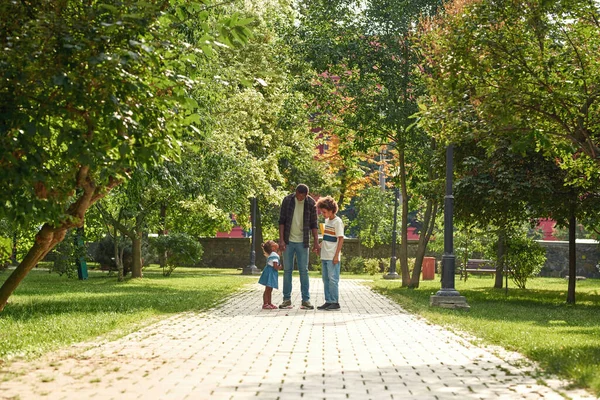 Otec a syn se dívají na dívku na silnici v zeleném parku — Stock fotografie