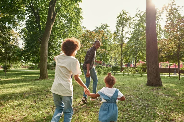 Joven familia negra jugando en el césped en el soleado parque —  Fotos de Stock