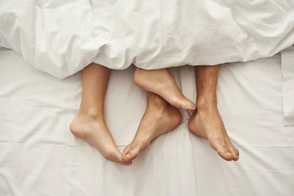 Gehaakt van blootsvoets voeten van man en vrouw op bed — Stockfoto