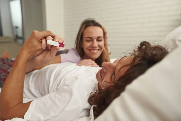 Meisje tonen zwangerschap test naar haar man op bed thuis — Stockfoto