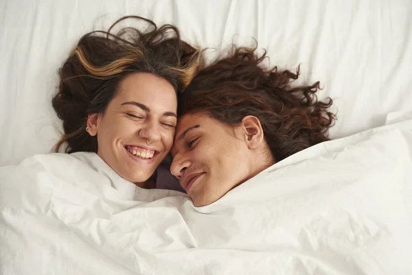 Top view of happy couple lay under blanket on bed — Fotografia de Stock