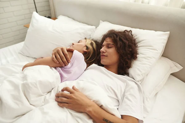 Tineri cuplu pune și dormi sub pătură pe pat — Fotografie, imagine de stoc
