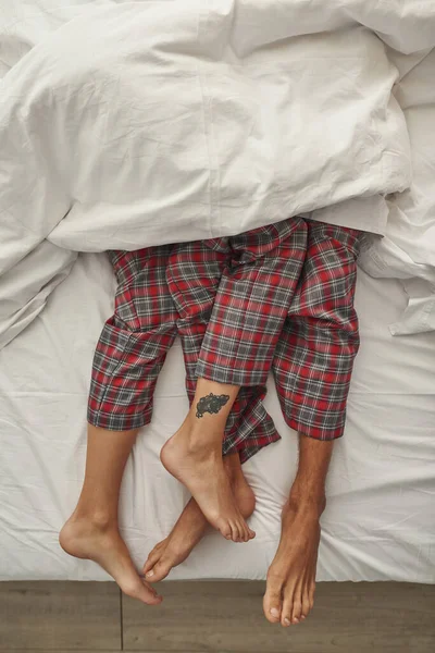 Partiell bild av par som ligger under filt på sängen — Stockfoto