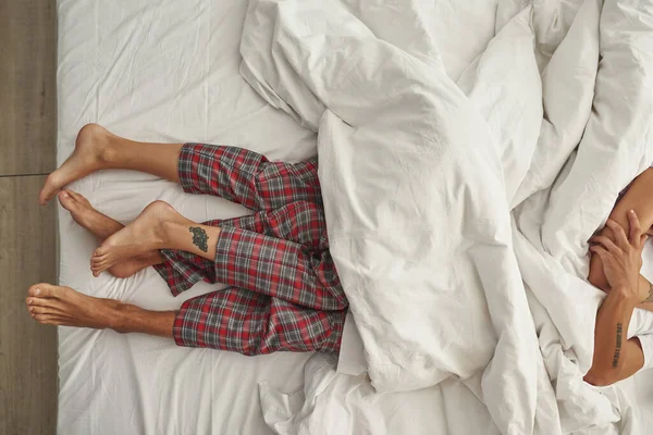 Gesneden beeld van paar liggend onder deken op bed — Stockfoto