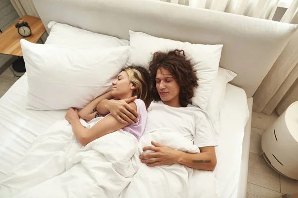 Верхній вид на молоду кавказьку пару спить на ліжку. — стокове фото