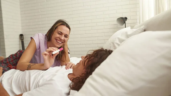 Menina mostrando teste de gravidez para cara na cama em casa — Fotografia de Stock