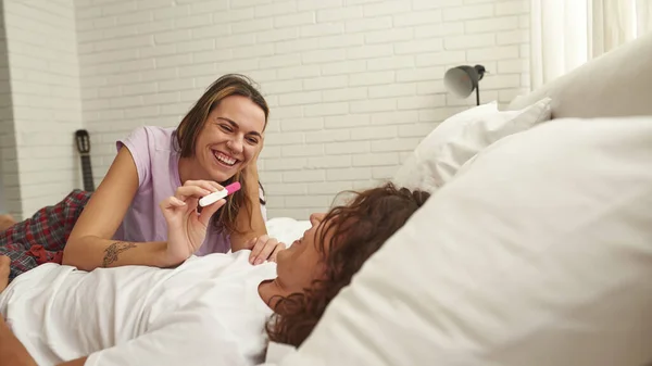 Meisje tonen zwangerschap test naar jongen op bed thuis — Stockfoto