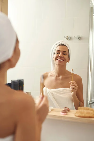 Mujer con cepillo de dientes orgánico mirando el espejo — Foto de Stock