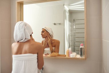 Genç kadın, banyoda aynada yüzüne bak.