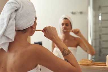 Kadın dişlerini organik bambu diş fırçasıyla fırçalıyor.