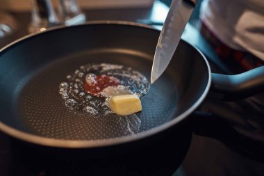 Tavada eriyen tereyağının üzerinde bıçağın kapağını kapat