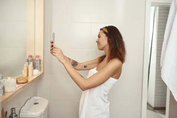 Chica tomar una foto de sí misma en el espejo en el teléfono inteligente — Foto de Stock