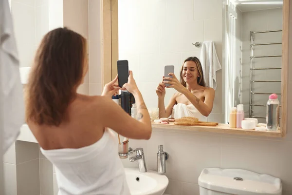 Mujer tomar una foto de sí misma en el espejo en el baño — Foto de Stock