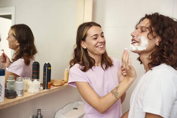 Caring girl smear foam on guy face before shaving — Foto de Stock