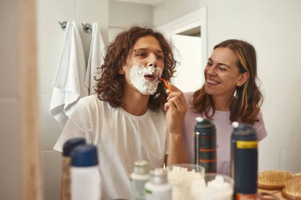 Girl looking at her boyfriend shaving with razor — Foto de Stock