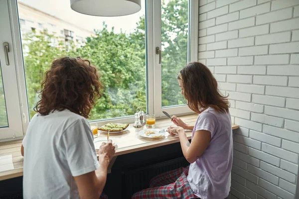 Pasangan makan telur goreng di meja windowsill — Stok Foto